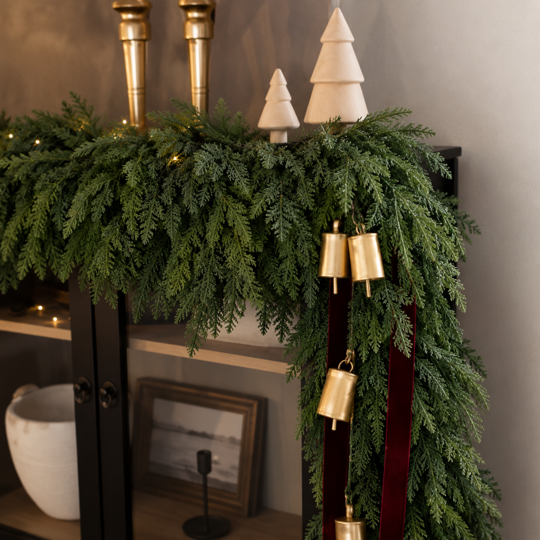 Cedar garland on a console with brass bells and velvet ribbon