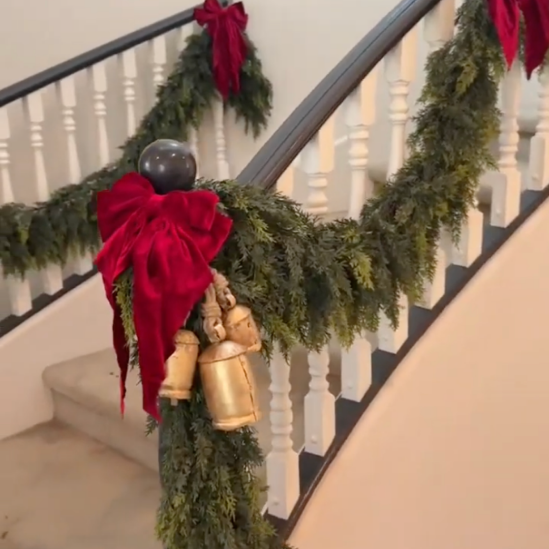Cedar garland on a staircase finished with deep red velvet bows